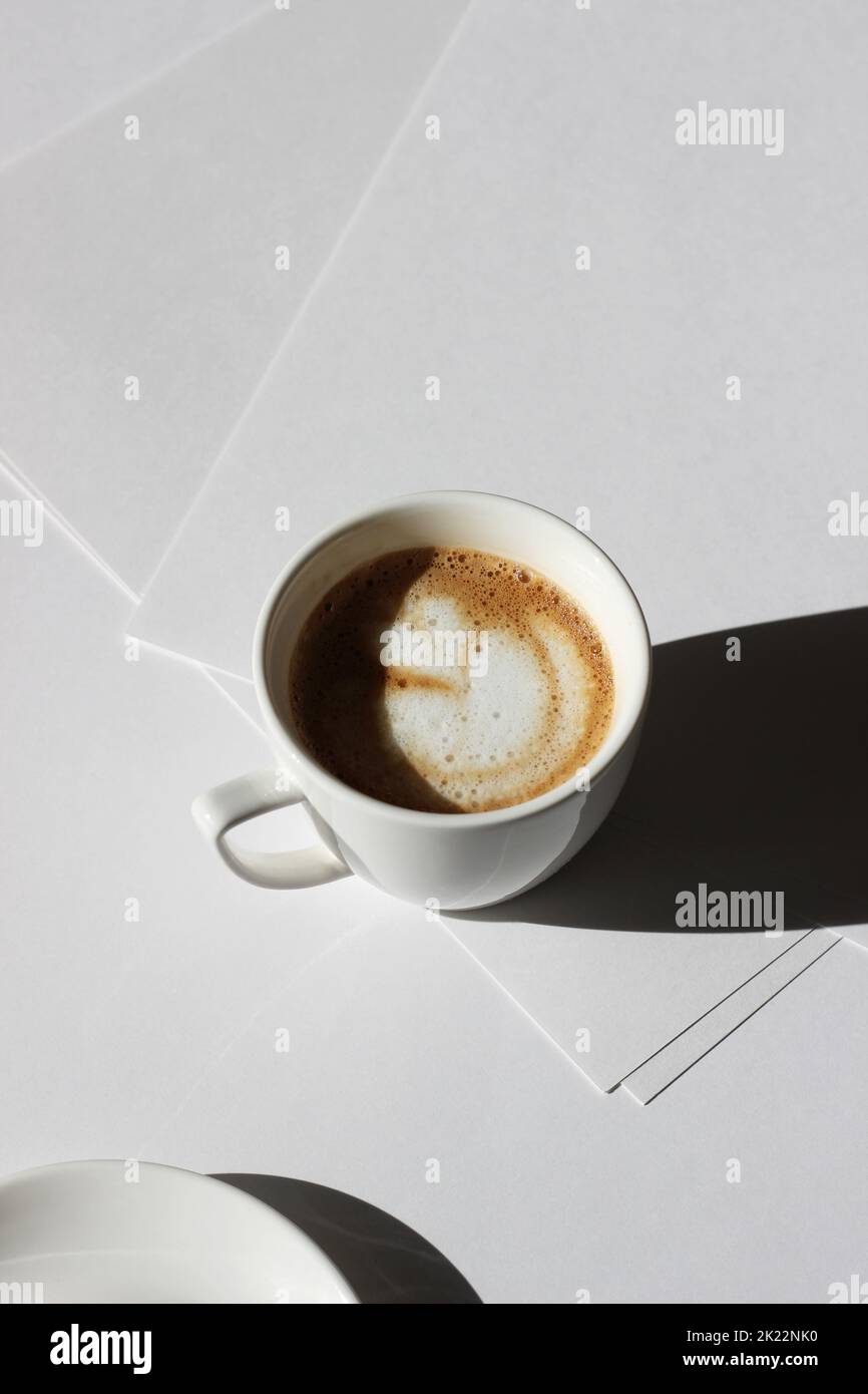 Frisch zubereiteter Cappuccino auf weißen Papierblättern. Minimaler Business Mockup. Stockfoto