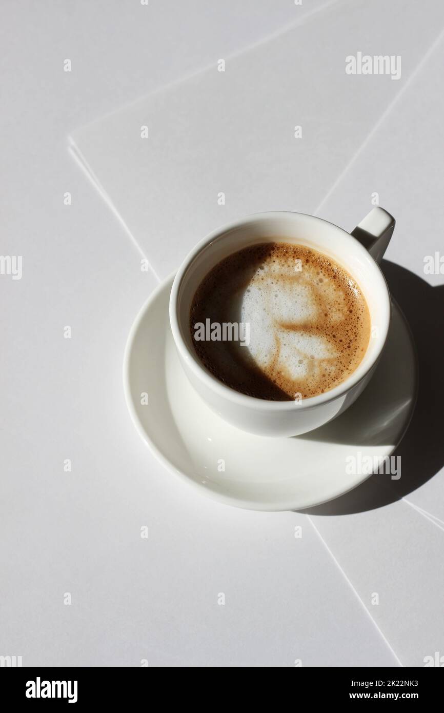 Minimaler Workplace Flatlay. Frischer Cappuccino mit Latte Art auf leeren Papierblättern, Business Design Concept Mockup. Stockfoto