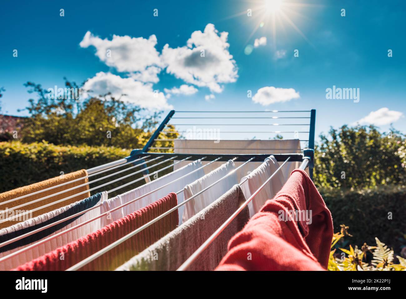 Trocknen Sie nasse Wäsche nach der Wäsche auf einem Trockengestell im Sommer in der Sonne, um Energie zu sparen, indem Sie keinen elektrischen Trockner verwenden. Stockfoto