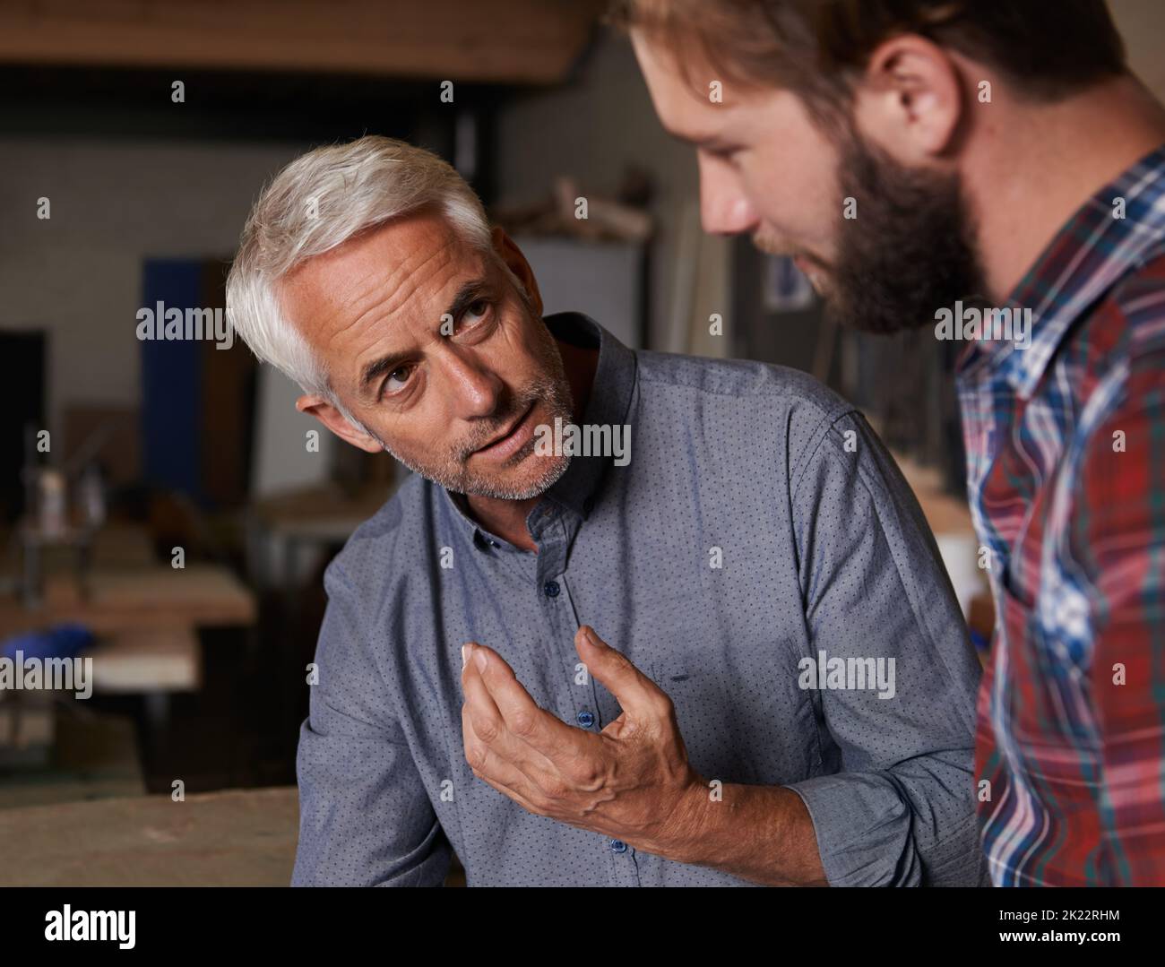 Sein ganzes Wissen weitergeben. Ein älterer Mann, der drinnen steht und seinen Sohn spricht. Stockfoto