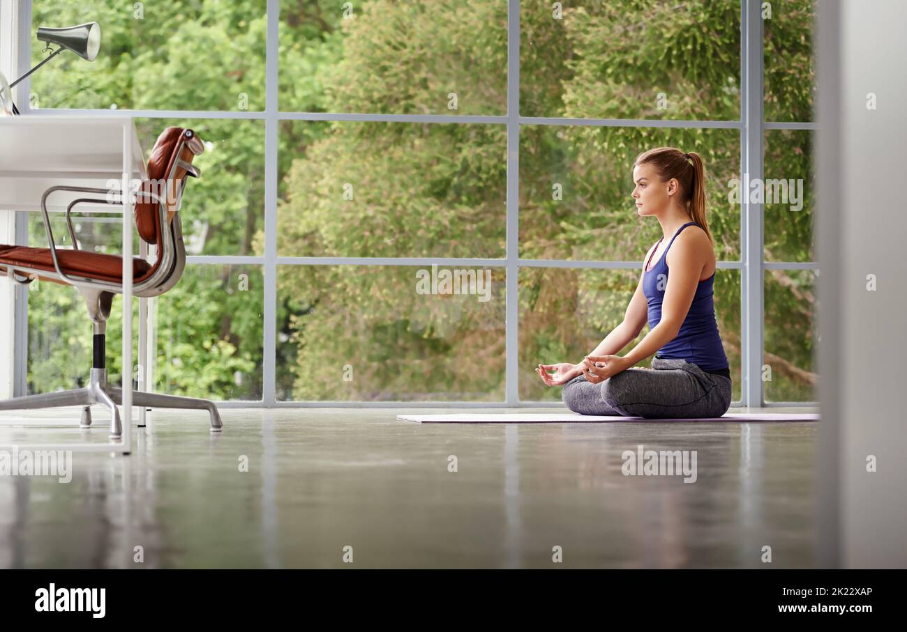 Ihr Zentrum finden. Ganzkörperaufnahme einer sportlichen Frau, die zu Hause Yoga praktiziert. Stockfoto