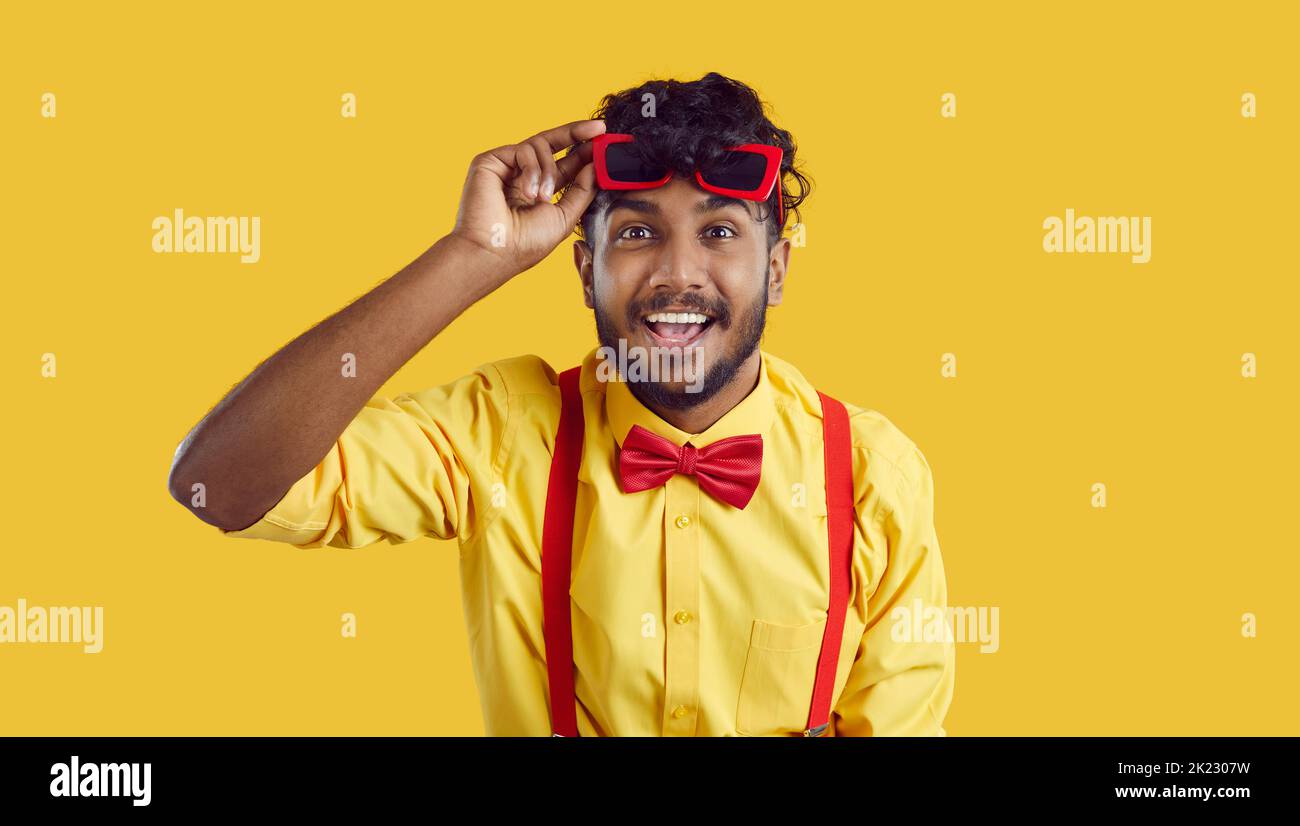 Junger fröhlicher südasiatischer Mann hebt lustige Gläser aus den Augen und schaut lächelnd auf den Bildschirm Stockfoto