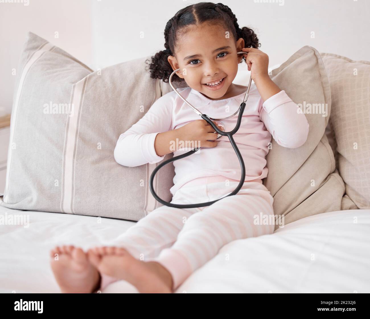 Doktor Spiel und Kind Porträt mit Stethoskop zu hören Herzschlag für Spaß Spielzeit im Schlafzimmer. Junges, niedliches und schwarzes Kind, das sich auf dem Bett mit einem Arzt entspannt Stockfoto
