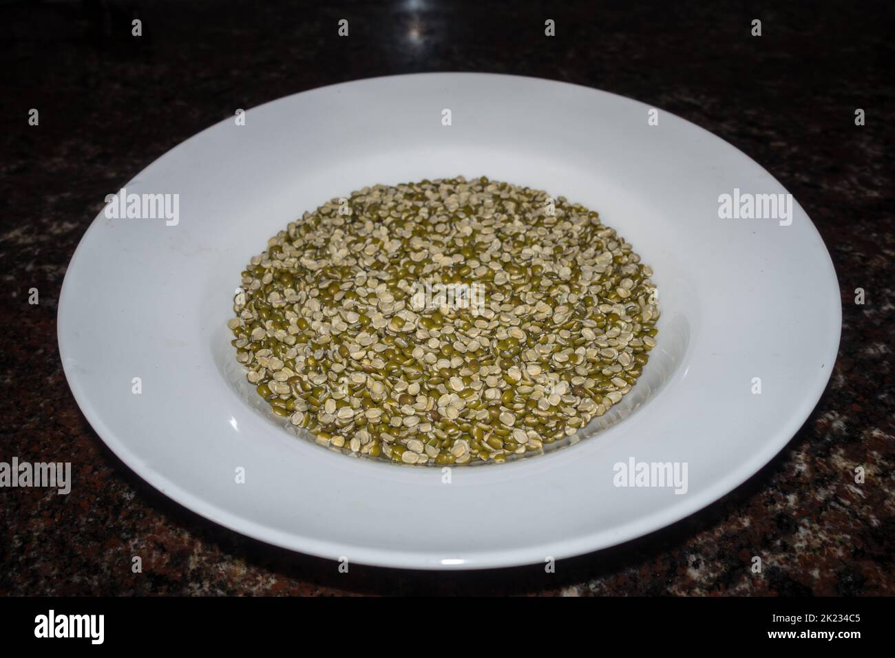 Getrockneter Split Moong Dal oder chilka Moong dal (Vigna radiata) auf einem weißen Teller in Studioaufnahmen. Uttarakhand Indien Stockfoto
