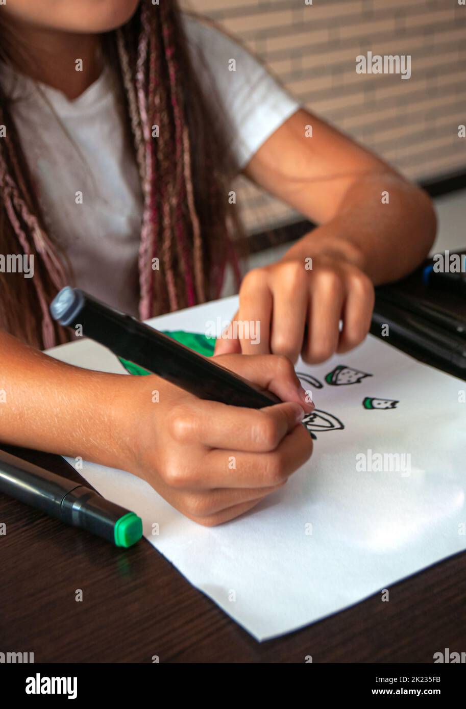 Ein glückliches kleines Mädchen zeichnet mit Markern. Stockfoto