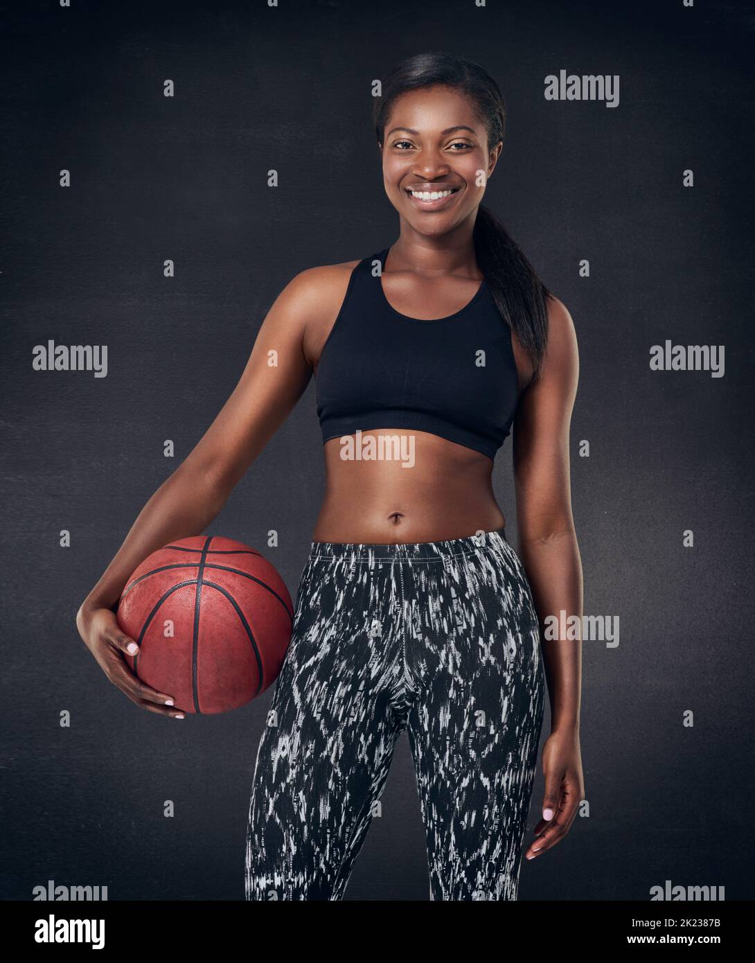 Lasst uns Basketball spielen. Studioaufnahme einer schönen jungen Frau, die einen Basketball vor schwarzem Hintergrund hält. Stockfoto