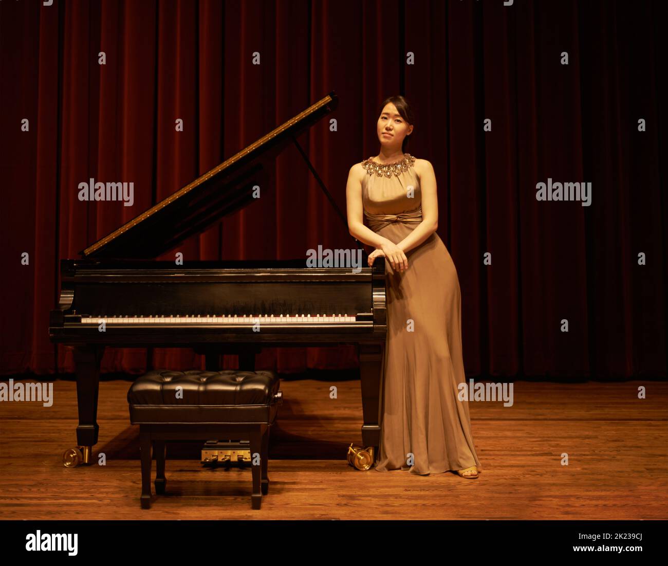 Eröffnungsabend. Eine junge Frau, die am Ende eines Musikkonzerts an ihrem Klavier steht. Stockfoto