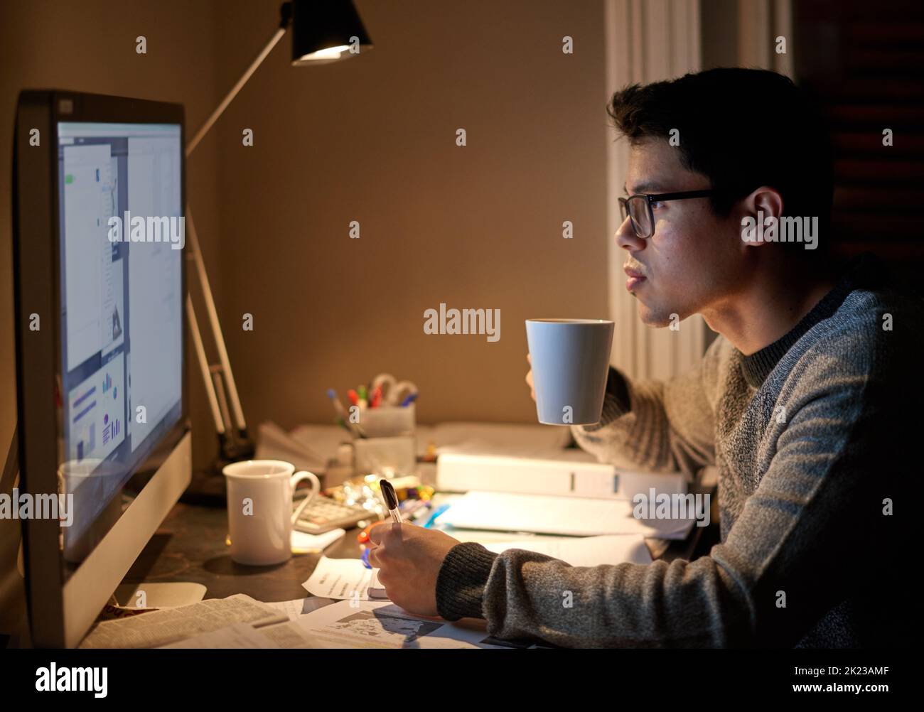 Etwas Koffein, um seine nächtliche Cram-Session zu unterstützen. Ein junger Student studiert bis spät in die Nacht. Stockfoto