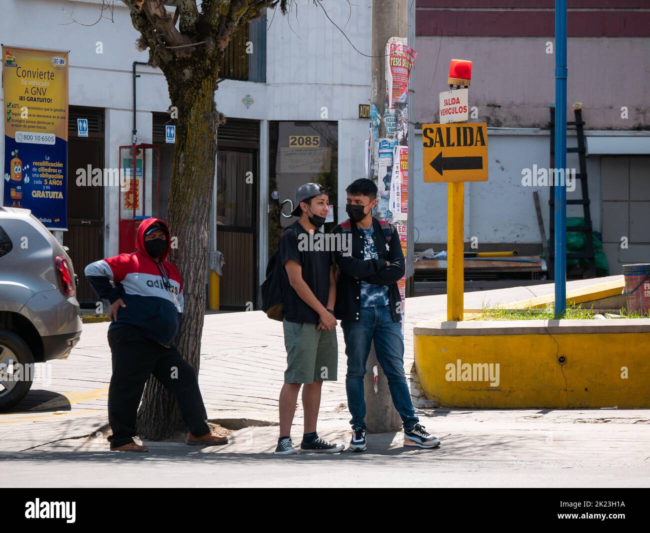 La Paz, Bolivien - 11 2022. September: Junge bolivianische Freunde mit schwarzen Masken warten mitten auf die öffentlichen Verkehrsmittel Stockfoto