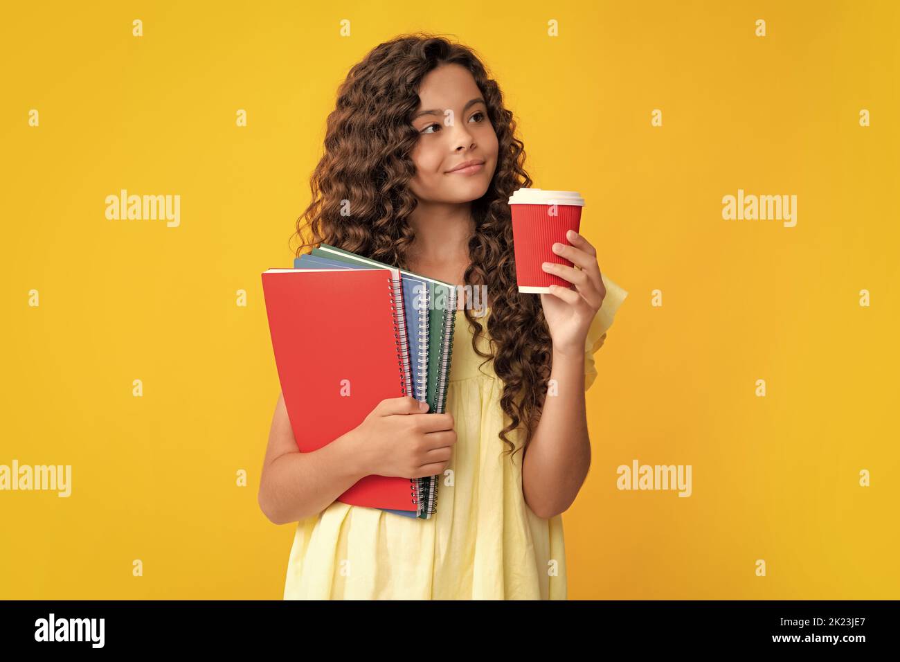 Morgen vor der Schule. Student teen Mädchen mit Büchern halten Takeaway Lieferung Tasse Kaffee auf gelbem Hintergrund isoliert. Bildung in College-Konzept Stockfoto
