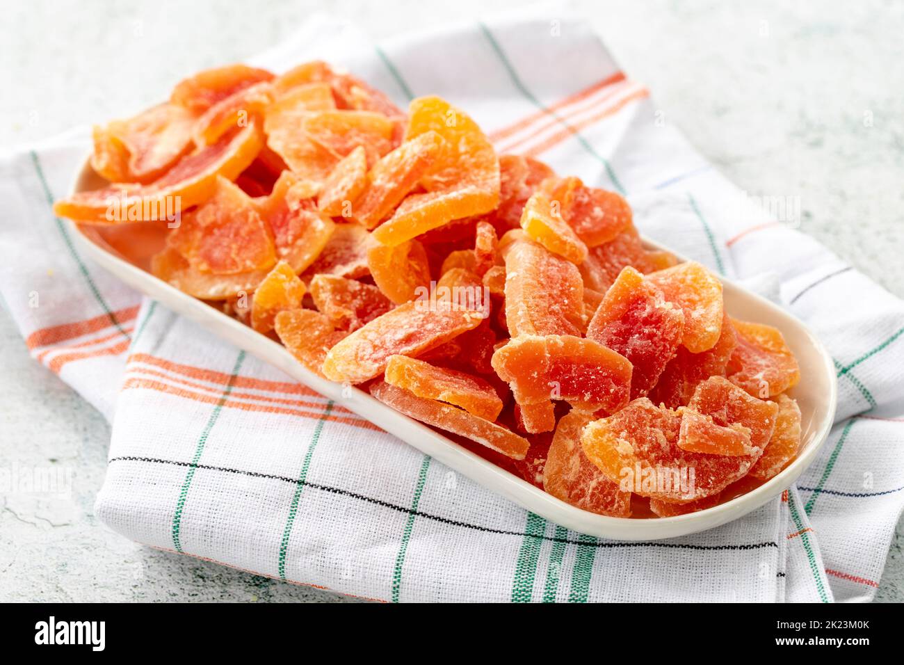 Getrocknete Papaya-Scheibe auf grauem Hintergrund. Getrocknete Früchte im Sonnenlicht. Nahaufnahme Stockfoto