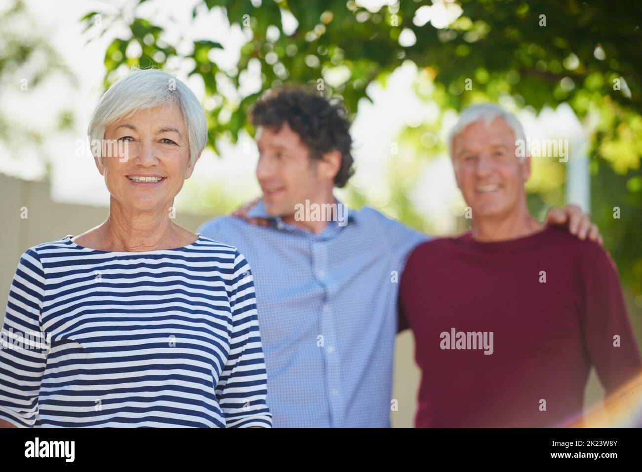 Ich liebe es, wenn er zu Besuch kommt. Beschnittenes Porträt eines älteren Paares, das mit ihrem Sohn draußen steht. Stockfoto