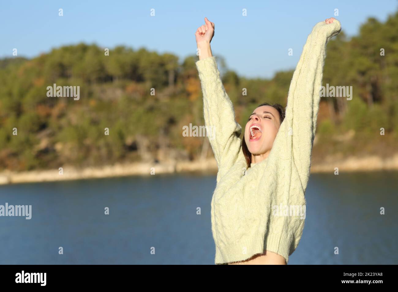 Aufgeregte Frau im Winter feiert Urlaub und rührende Arme in einem See Stockfoto