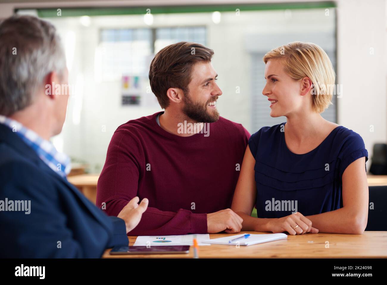Du hier das. Junges Paar diskutiert Investitionspläne mit einem Finanzberater. Stockfoto