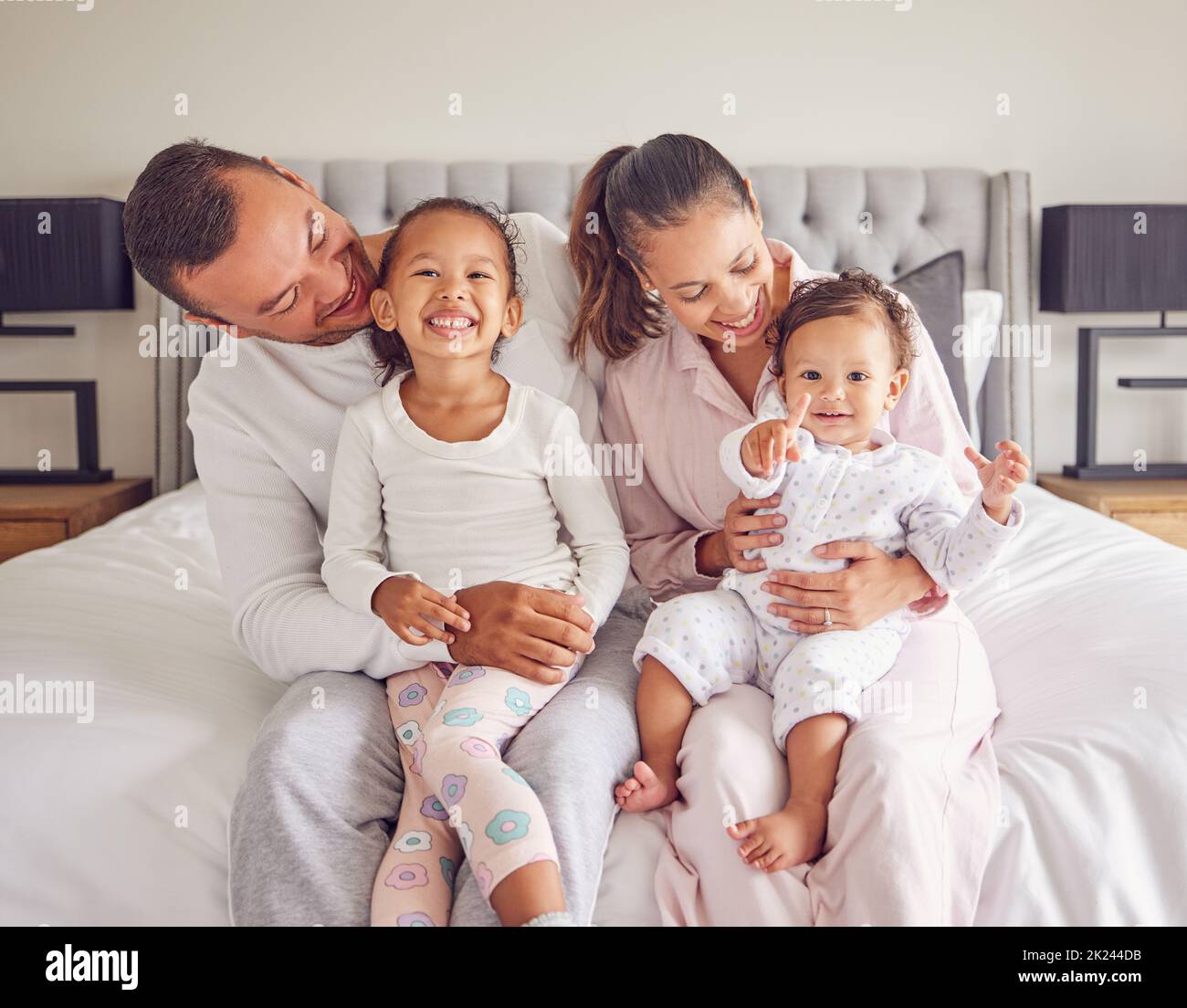 Glücklich, lächelnd und eine Familie im Schlafanzug auf dem Bett mit kleinen Mädchen. Junge Mutter und Vater mit Mädchen Kinder im Schlafzimmer am Morgen. Liebe, Lächeln und Stockfoto