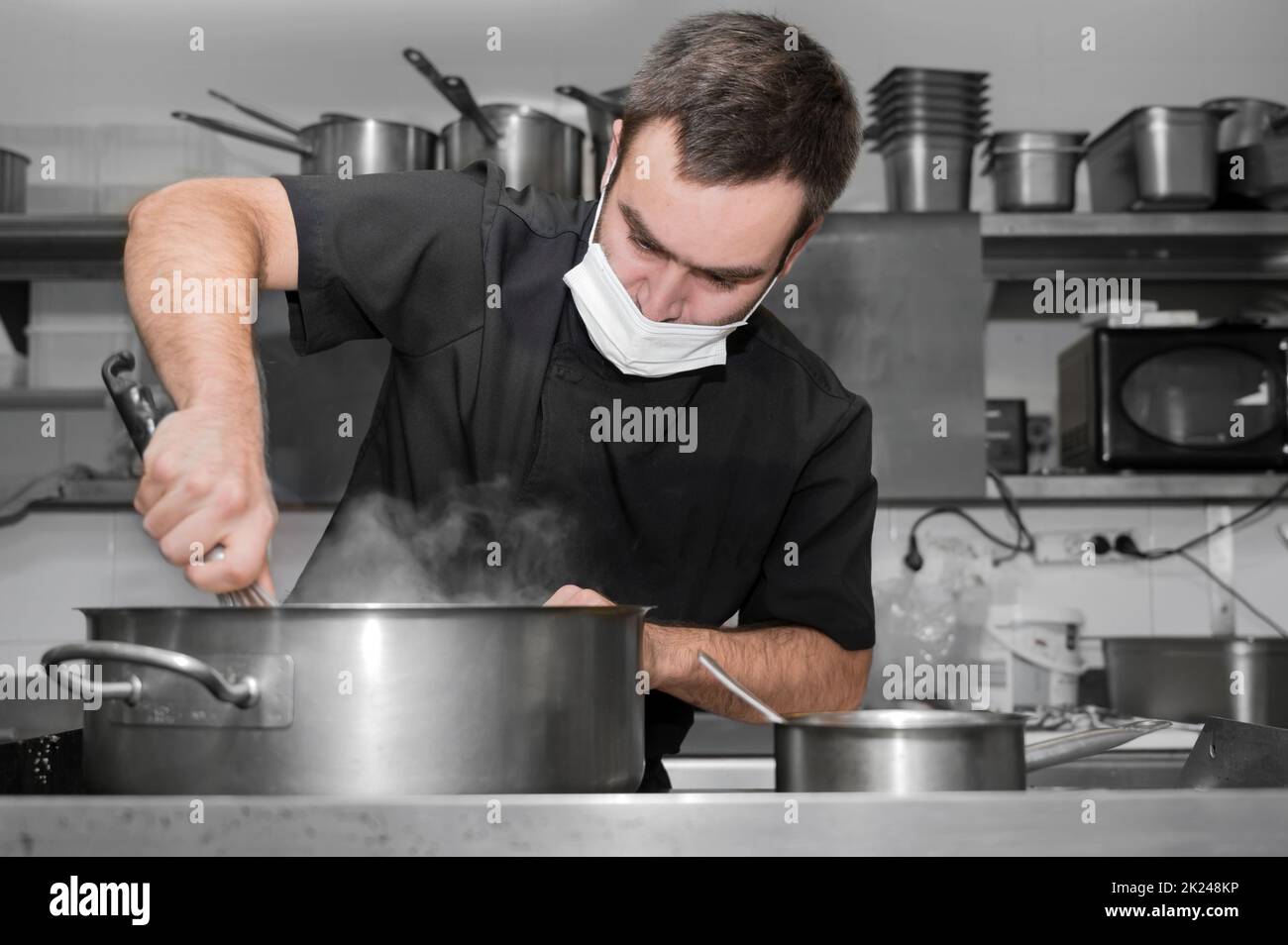 Koch Rührsoße in Edelstahltopf, Nahaufnahme. Professionelle Küche, Restaurant. Hochwertige Fotos Stockfoto