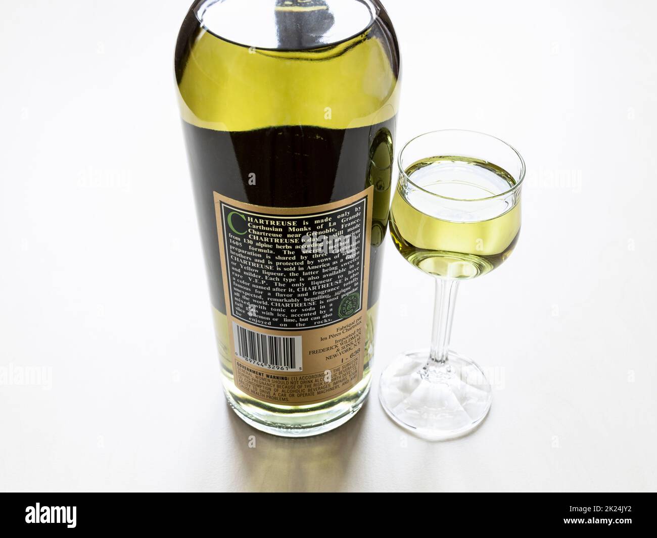 Moskau, Russland - 3. Februar 2022: Rückseite der Flasche mit grünem Chartreuse-Likör aus den USA und Likörglas auf hellem Tisch. Der Likör wurde hergestellt Stockfoto