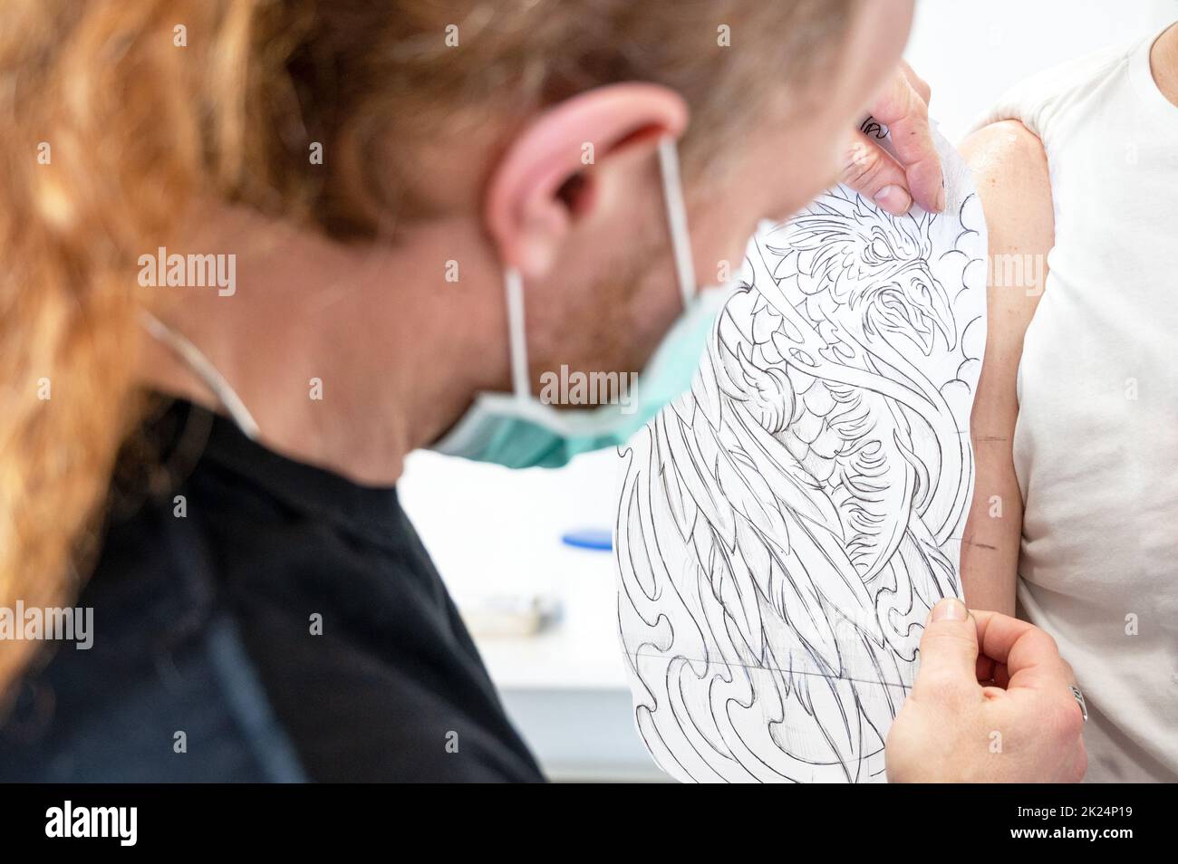 Ein erfahrener Tattoo-Künstler, der eine Skizze auf den Arm eines Mannes legt. Hochwertige Fotos Stockfoto