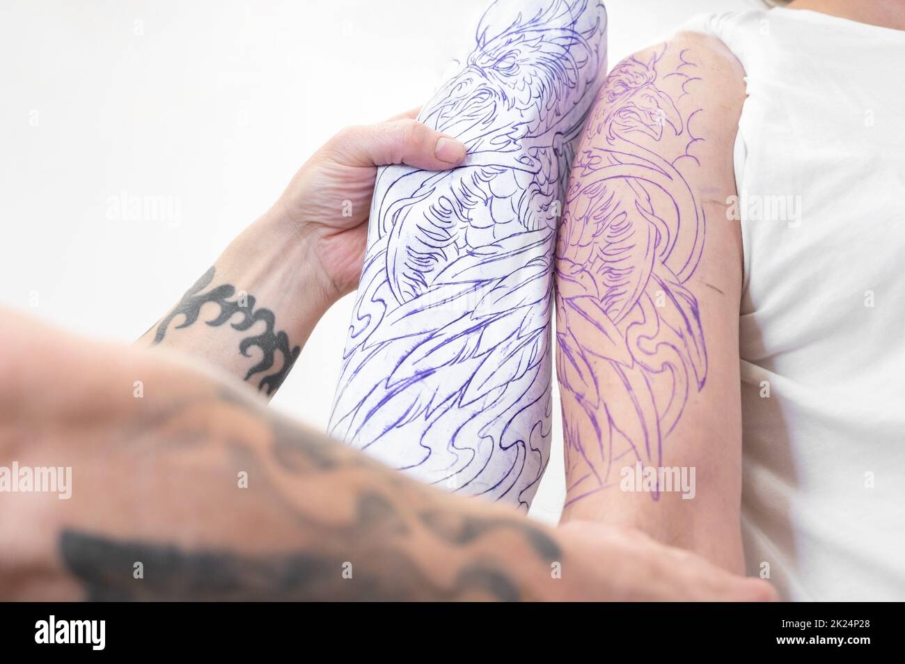 Ein erfahrener Tattoo-Künstler, der eine Skizze auf den Arm eines Mannes legt. Hochwertige Fotos Stockfoto