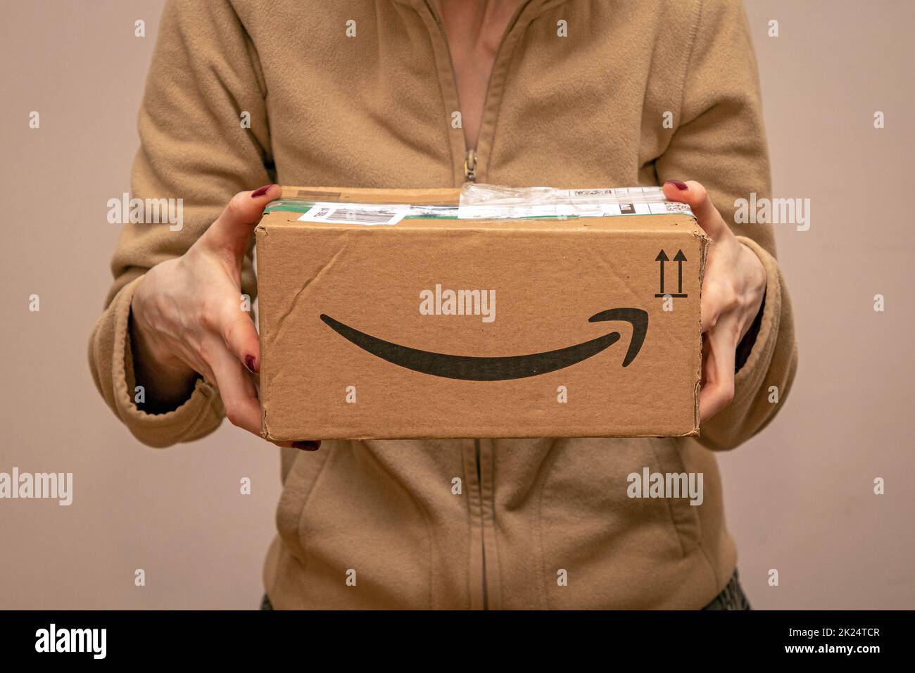 London, Vereinigtes Königreich - 10. Dezember 2021: Frau hält ein geschlossenes Papppaket in den Händen, nachdem ben das Paket von Amazon nach Hause geliefert hat Stockfoto