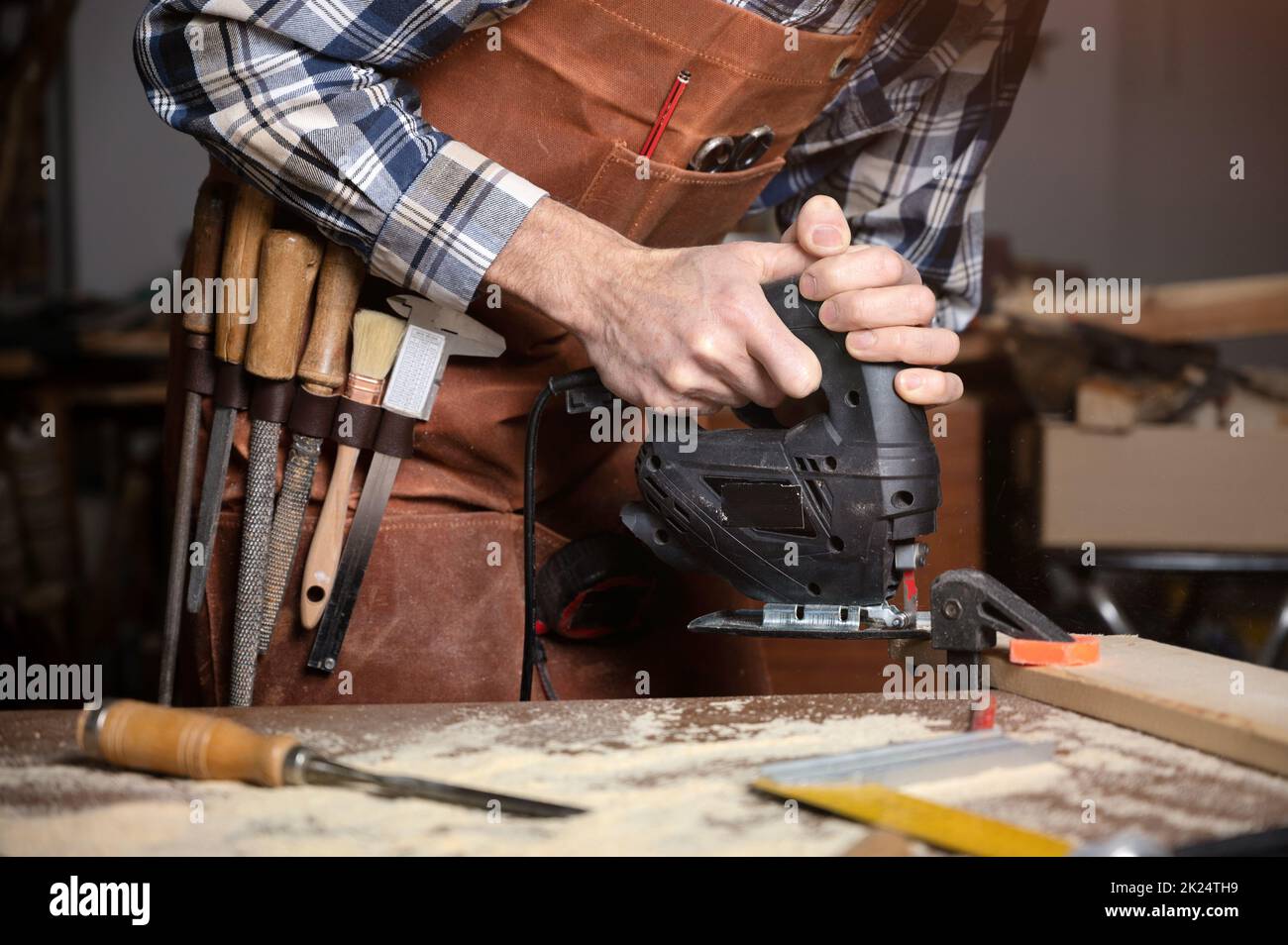 Zimmermann sägt in der Schreinerei eine Holzdiele mit elektrischer Stichsägemaschine. Arbeitholz DIY Konzept. Hochwertige Fotografie. Stockfoto