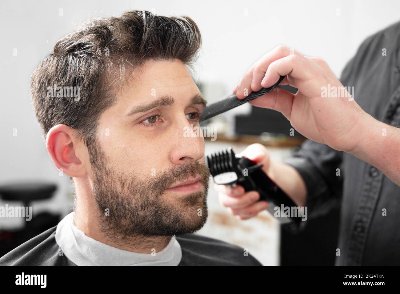Mann Barbier schneiden Haare von männlichen Kunden mit Haarschneider im Friseurladen. Haarstyling-Prozess. Hochwertige Fotografie Stockfoto