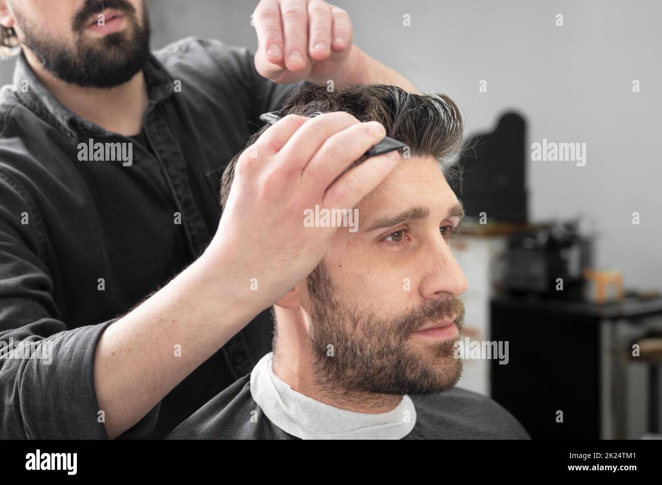 Mann Barbier schneiden Haare von männlichen Kunden mit Haarschneider im Friseurladen. Haarstyling-Prozess. Hochwertige Fotografie Stockfoto