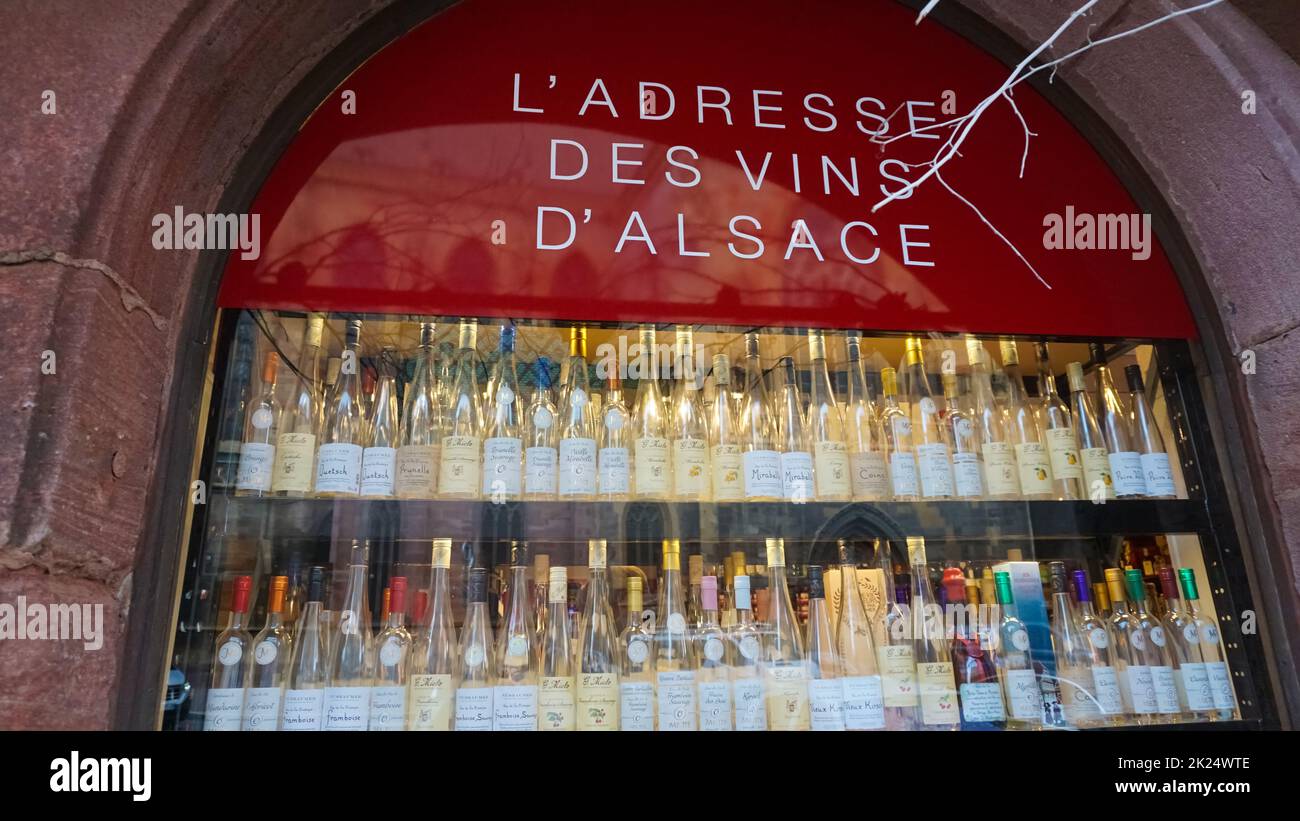 Colmar, Frankreich - 30. Dezember 2021: Mehrere Flaschen erlesener Weine, die auf Holzregalen in der Nähe von Kisten in einem lokalen Geschäft gelagert werden. Elsässische Weinstraße. Reisen und nach Stockfoto