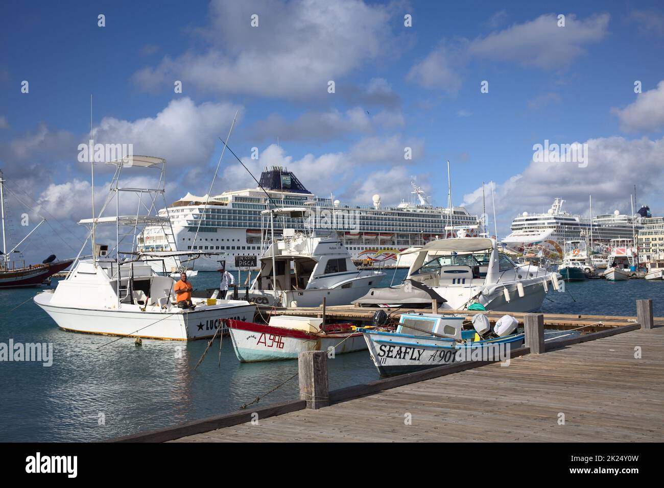 ORANJESTAD, ARUBA - 14. DEZEMBER 2020: Fischerboote in der Wind Creek Marina, dahinter die Norwegische Sonne und die Norwegischen Pearl-Schiffe der N Stockfoto