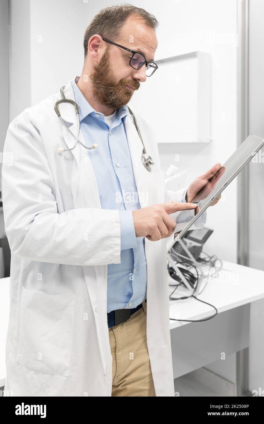Männlicher Arzt mit weißem Mantel und Stethoskop mit Tablet, Netzwerkanbindung im Krankenhauszimmer, Medizintechnik-Netzwerkkonzept. Hochwertige Fotos Stockfoto