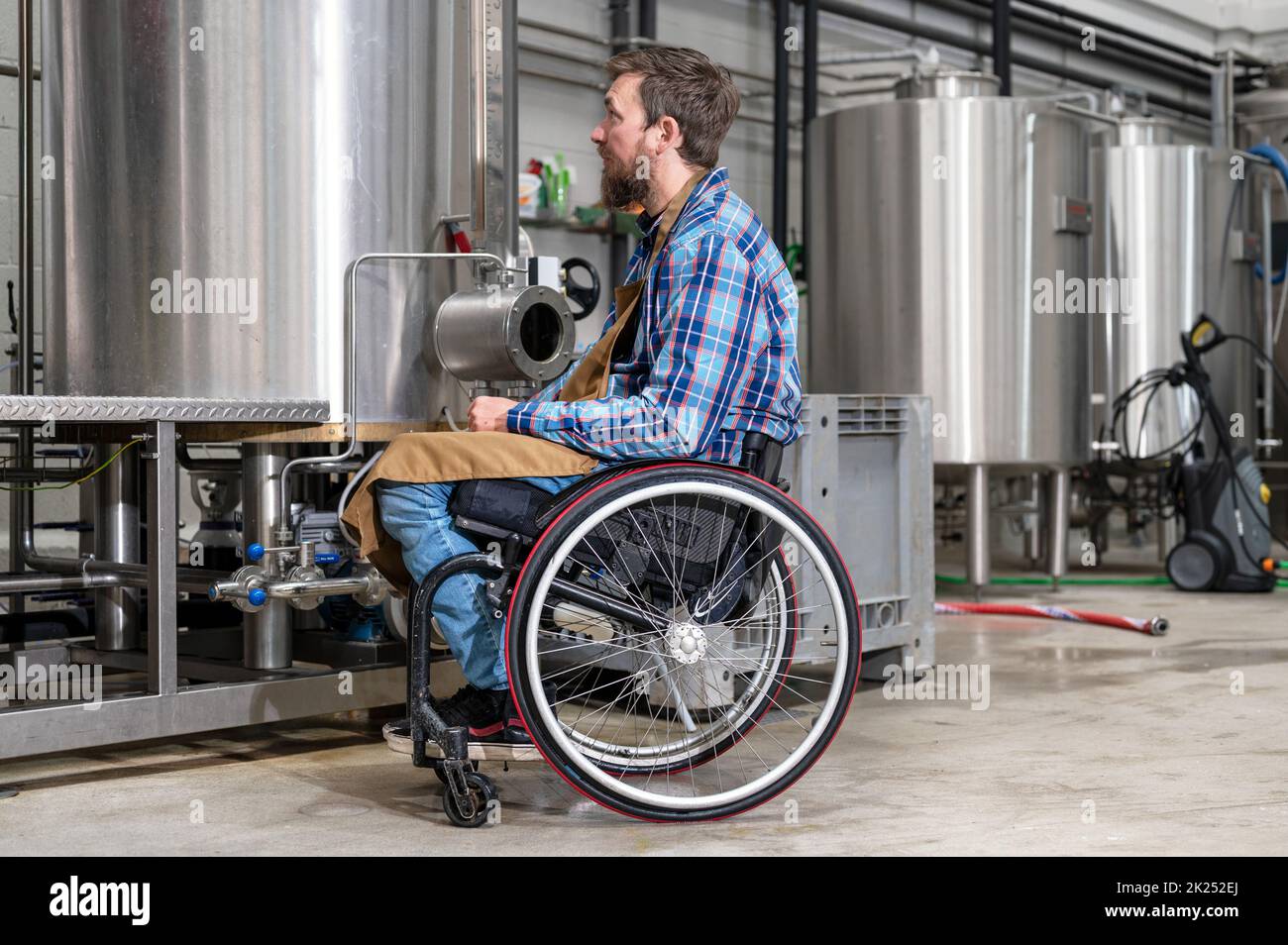 Mann im Rollstuhl, der in der Brauerei-Fabrik arbeitet. Hochwertige Fotografie Stockfoto
