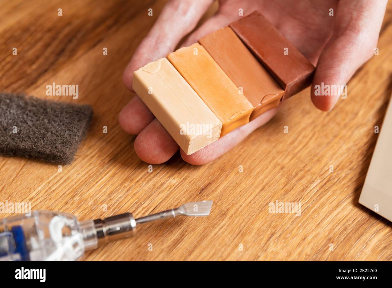 Mann passende Farbe von hartem Wachs für Reparatur Risse, Kratzer, Beulen im Holzboden. Professionelles Reparaturset Laminat oder Parkett mit Hartwachs stic Stockfoto