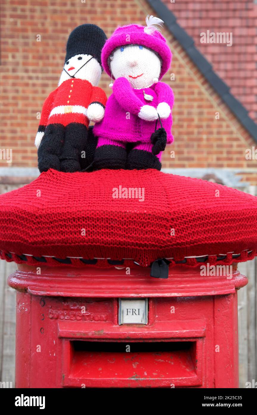 Skurrile bunte handgemachte gestrickte Wollmütze ziert eine traditionelle rote Säulenbox, die das Platin-Jubiläum von Königin Elizabeth II. Feiert 2022, GROSSBRITANNIEN. Stockfoto