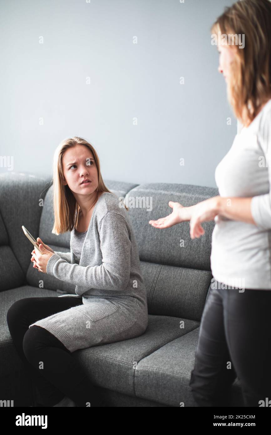 Kampf um die Bildschirmzeit – Teenager-Tochter, die unglücklich darüber ist, dass ihre Mutter ihre Bildschirmzeit auf einem Tablet-Computer einschränkt Stockfoto