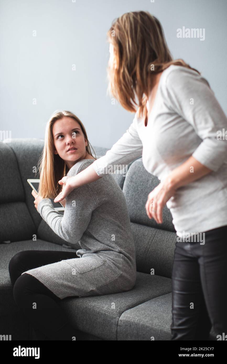 Kampf um die Bildschirmzeit – Teenager-Tochter, die unglücklich darüber ist, dass ihre Mutter ihre Bildschirmzeit auf einem Tablet-Computer einschränkt Stockfoto