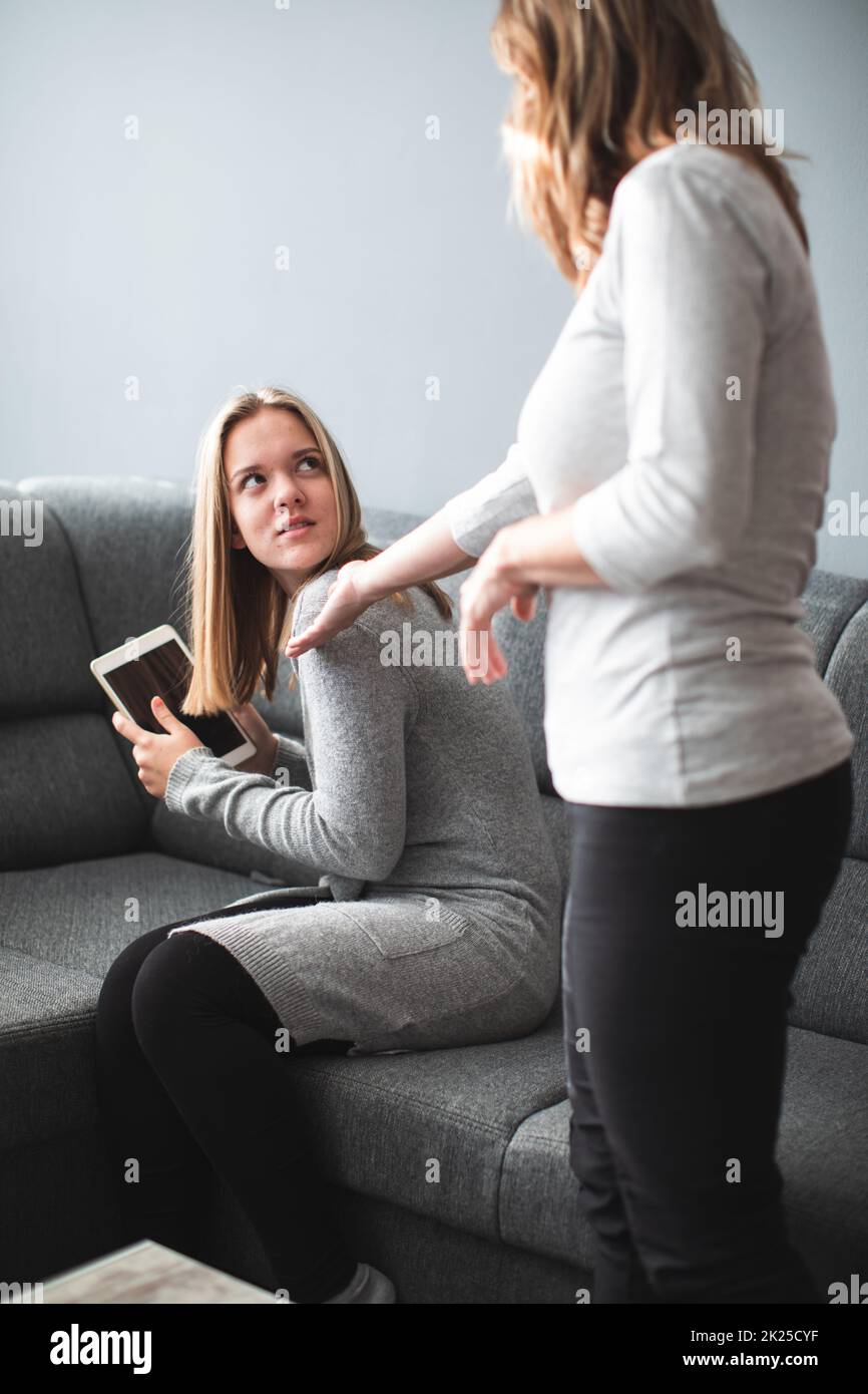 Kampf um die Bildschirmzeit – Teenager-Tochter, die unglücklich darüber ist, dass ihre Mutter ihre Bildschirmzeit auf einem Tablet-Computer einschränkt Stockfoto
