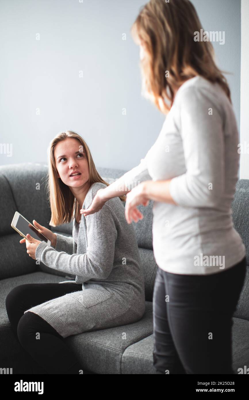 Kampf um die Bildschirmzeit – Teenager-Tochter, die unglücklich darüber ist, dass ihre Mutter ihre Bildschirmzeit auf einem Tablet-Computer einschränkt Stockfoto