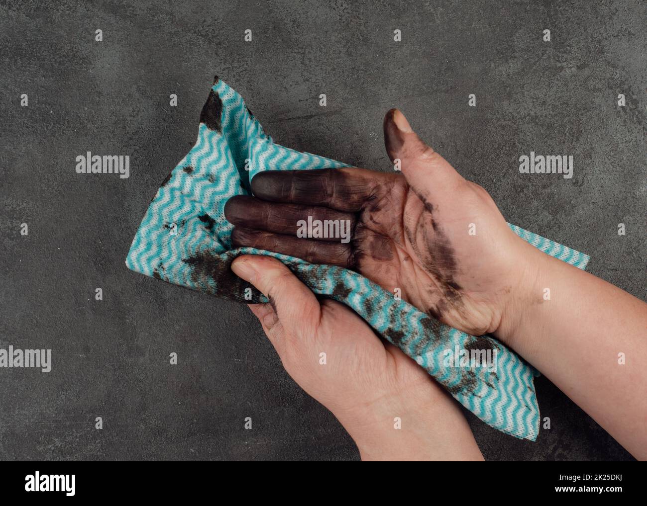 Reinigung schmutziger Hände mit einem Kleidungsstück, Heizöl, Mechaniker, Reparaturservice, dunkler Hintergrund Stockfoto