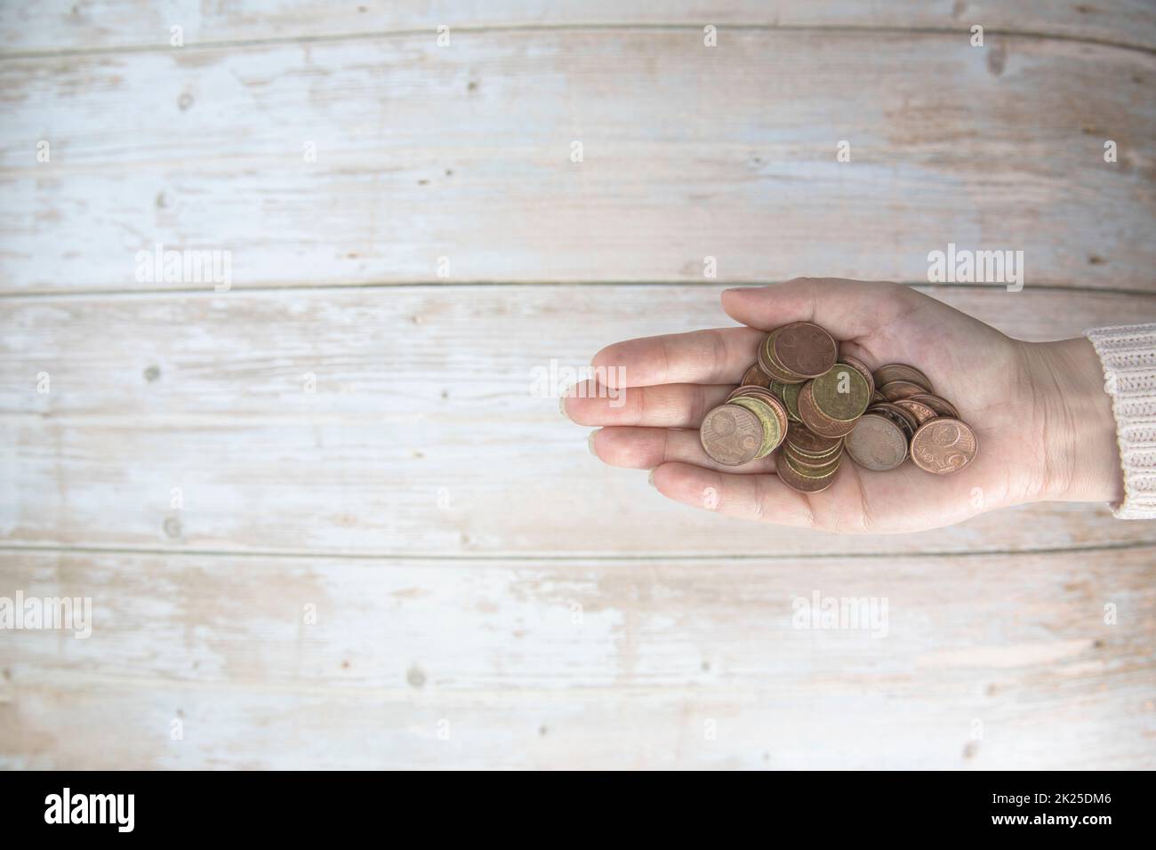 Hände, die einen Haufen Euro-Münzen in der Hand halten, auf Holzhintergrund. Spenden, Sparen, Spendenaktionen, Familienfinanzplan, Finanzkrisenkonzept. Draufsicht. Speicherplatz kopieren Stockfoto