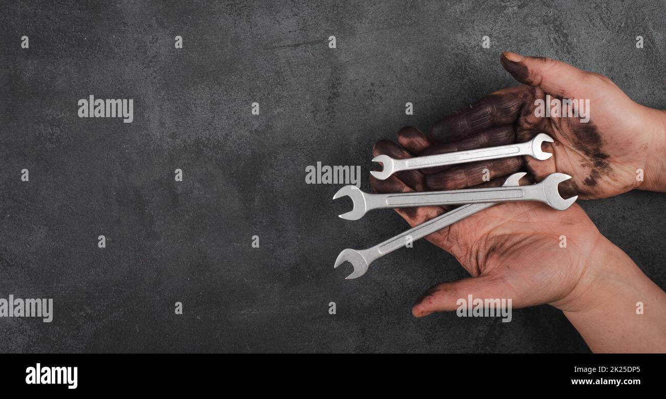 Halten Sie Schlüsselwerkzeuge in den Händen, bedeckt mit Heizöl, Reparaturwerkzeuge, Industriearbeiter, Kopierspachtel Stockfoto