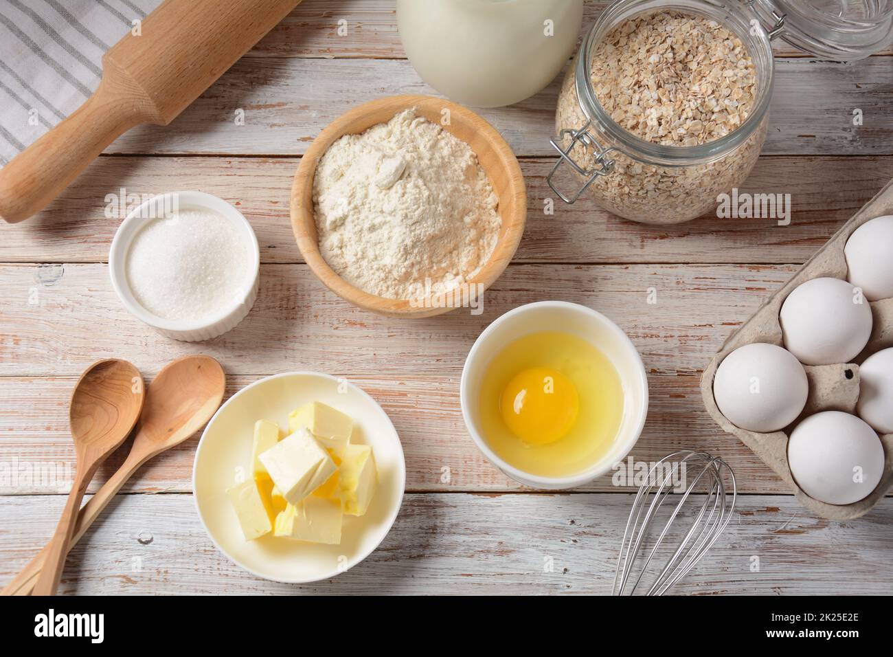 Rahmen aus Zutaten zum Backen auf weißem Hintergrund. Mehl, Eier, Zucker und Milch in weißen und hölzernen Schüsseln. Koch- und Backkonzept. Stockfoto