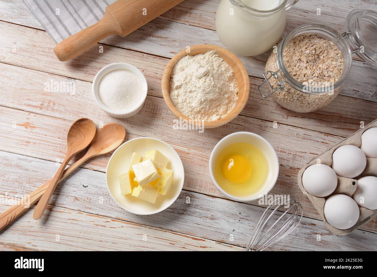 Rahmen aus Zutaten zum Backen auf weißem Hintergrund. Mehl, Eier, Zucker und Milch in weißen und hölzernen Schüsseln. Koch- und Backkonzept. Stockfoto