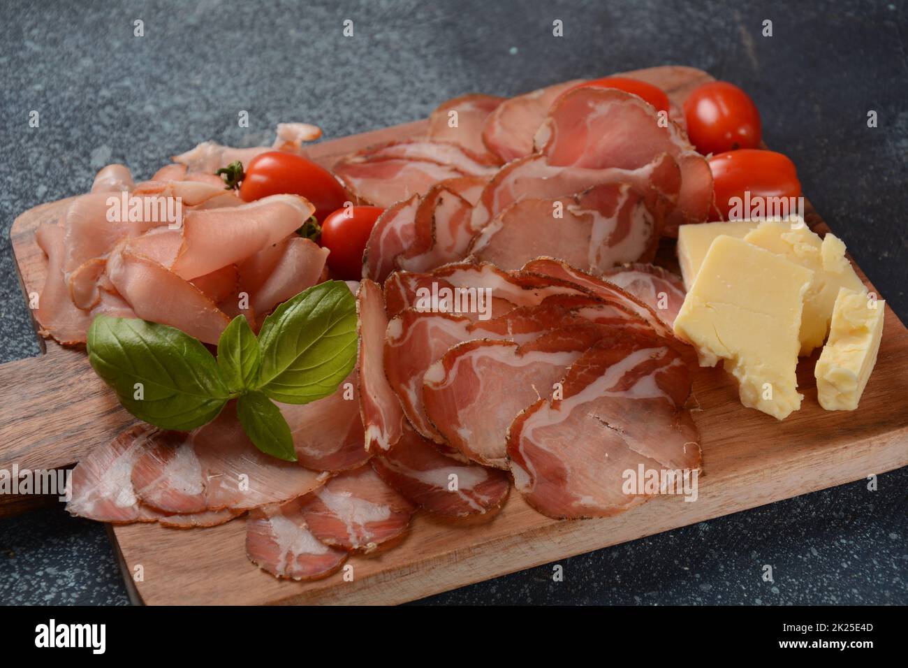 Italienische gehärtete Schweineschulter. Antipasto-Platte coppa stagionata und Kirschtomaten. Traditionelle Wurst in Scheiben mit Gewürzen Stockfoto