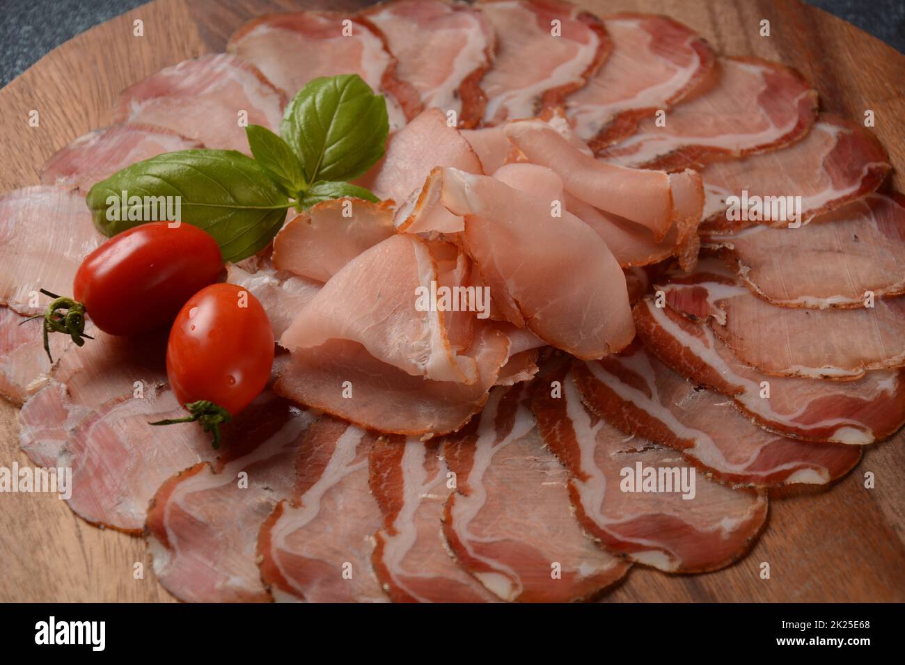 Italienische gehärtete Schweineschulter. Antipasto-Platte coppa stagionata und Kirschtomaten. Traditionelle Wurst in Scheiben mit Gewürzen Stockfoto