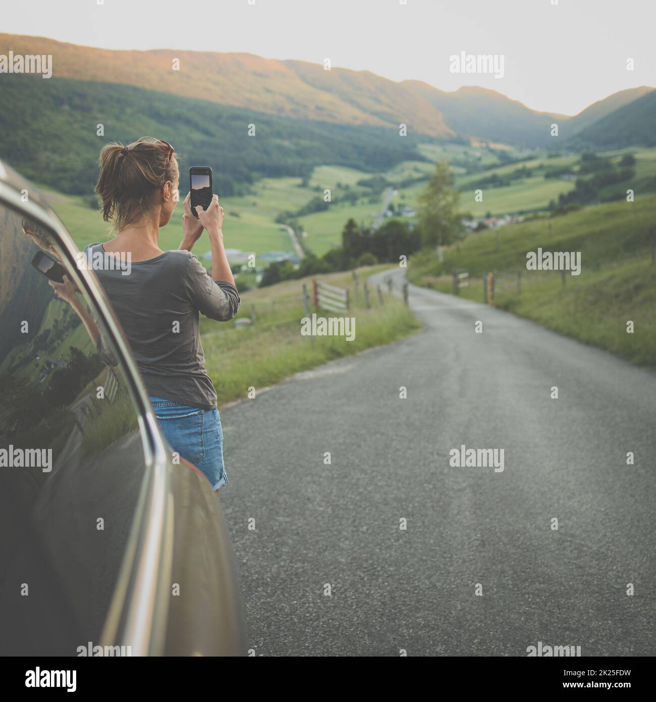 Unterwegs in der Natur fotografiert die Frau mit ihrem Smartphone die alpine Landschaft Stockfoto