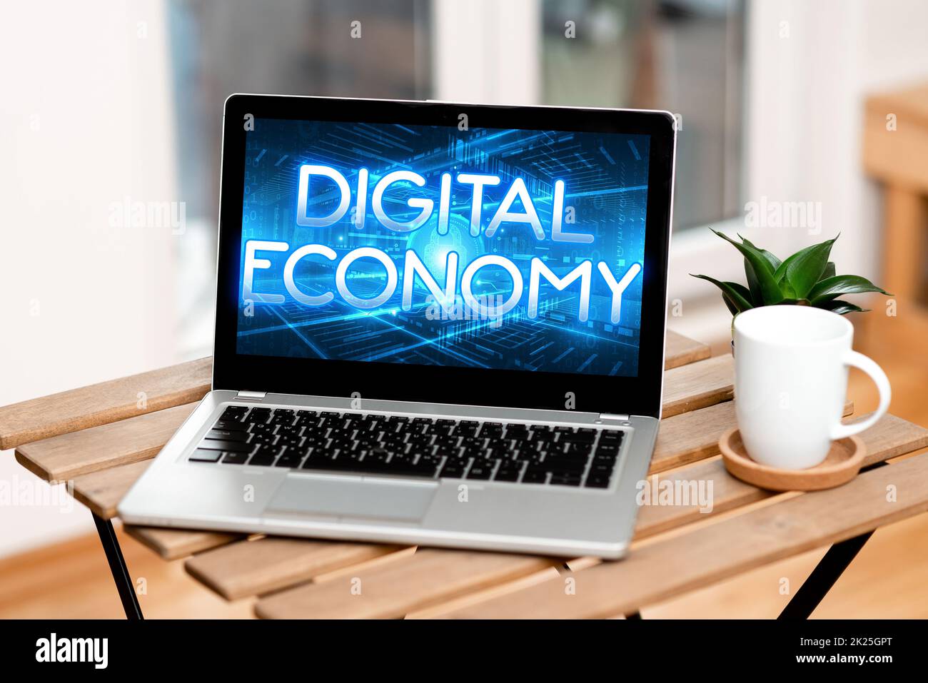 Textzeichen für die digitale Wirtschaft. Geschäftsansatz weltweites Netzwerk von wirtschaftlichen Aktivitäten und Technologien Laptop auf einem Tisch neben Kaffeetasse und Pflanze Arbeitsablauf zeigen. Stockfoto