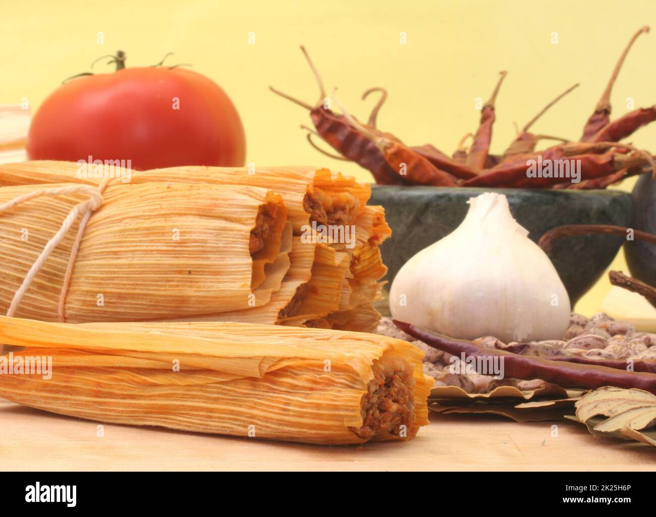 Tamales mit Knoblauch, Bohnen und Tomate auf gelbem Hintergrund Stockfoto