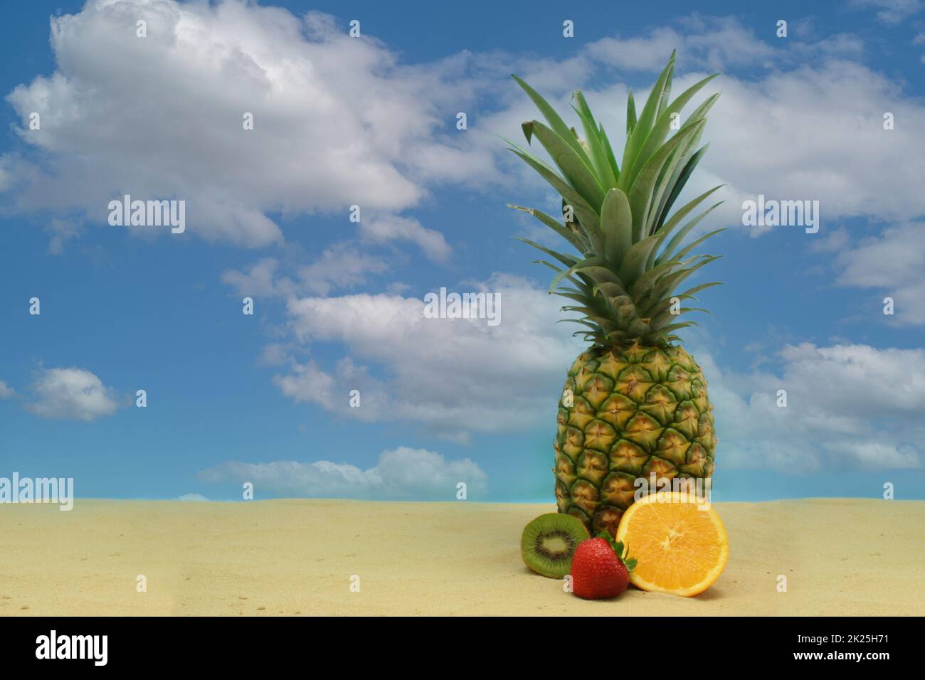 Ananas, tropisches Getränk und Obst auf Sand mit Himmel Stockfoto