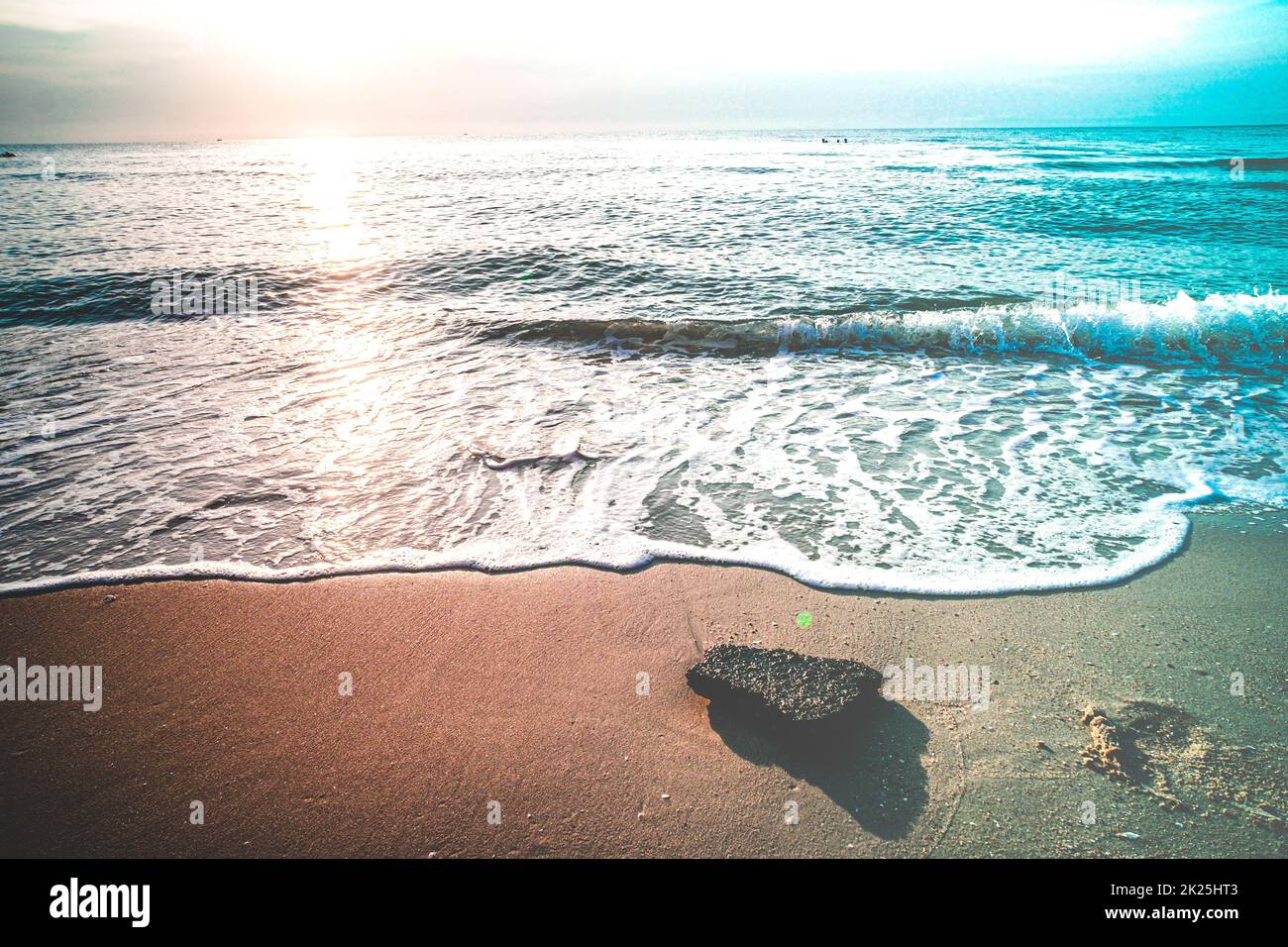 Sanfte blaue Wellen am Strand im Sommer. Meeresstrand blauer Himmel, Sonne, Tageslicht, Relaxationslandschaft Aussichtspunkt. Die Farbe des Wassers und das wunderbar helle, klare Wasser. Stockfoto