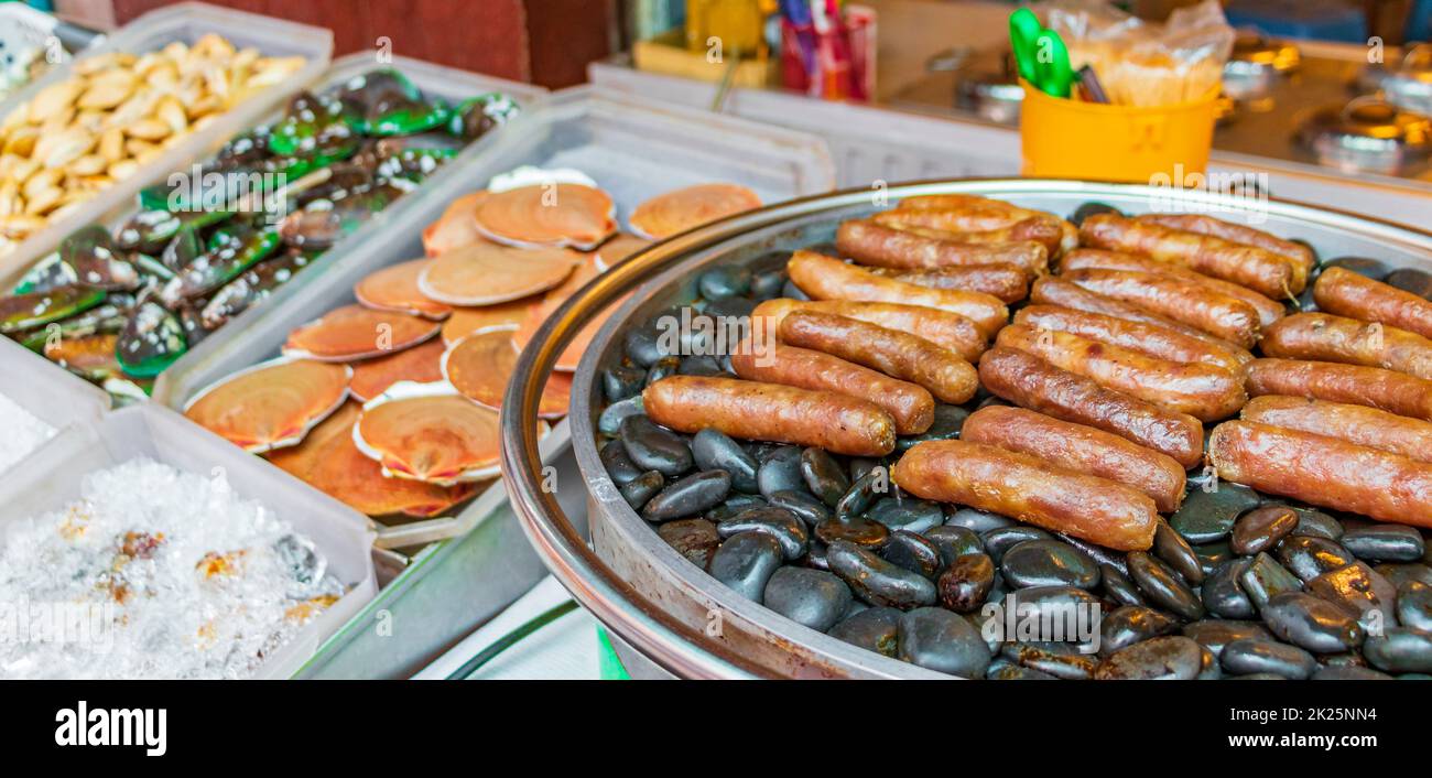 Gegrillte Würstchen auf heißen Steinen, thailändischer Markt, China Town Bangkok. Stockfoto